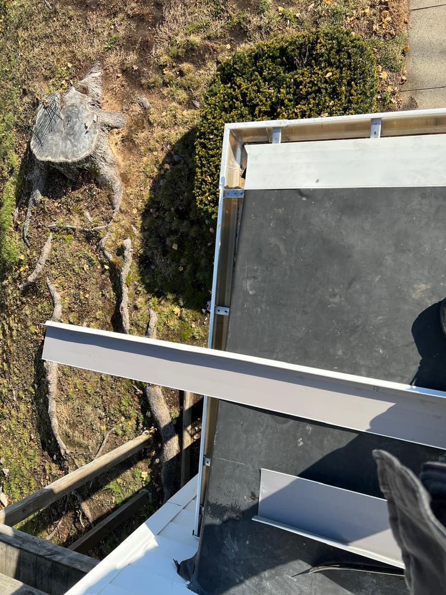 New white drip edge along a rebuilt flat-roof edge.