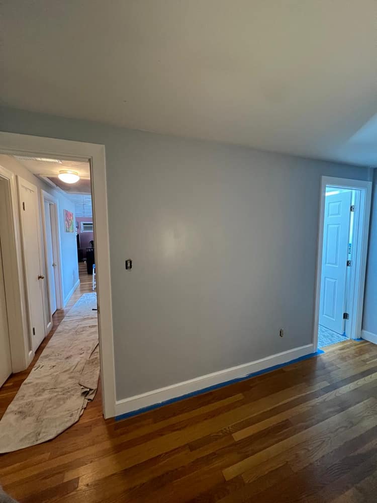 A finished interior repaint in soft blue-gray, with crisp white trim and doors over refinished hardwood.