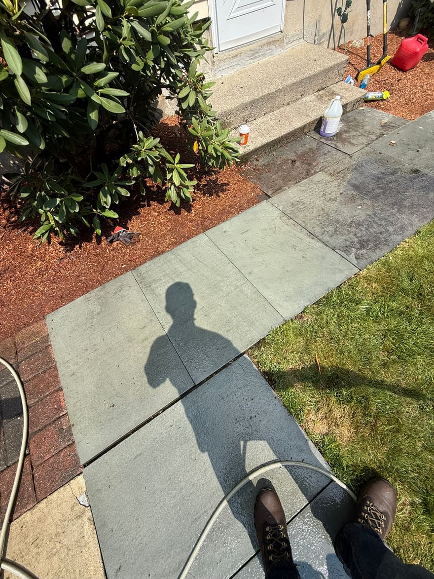 A stone walkway mid-wash, the cleaned section against the untouched stone.