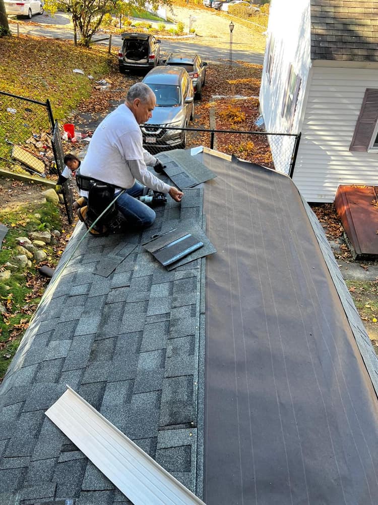 Shingling down to the rubber membrane where the pitched roof meets a flat section.