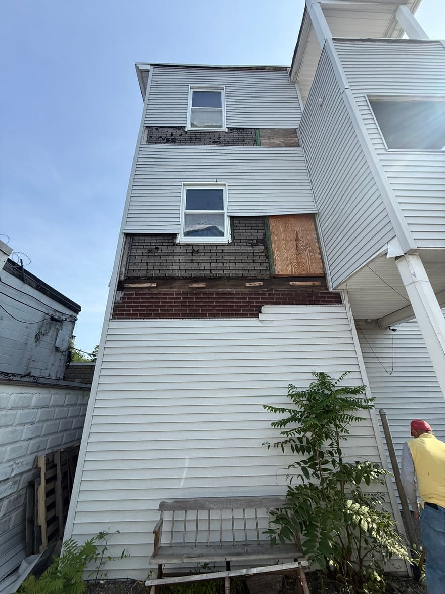 Old siding stripped back on a three-story exterior, ready for the wall to be addressed.
